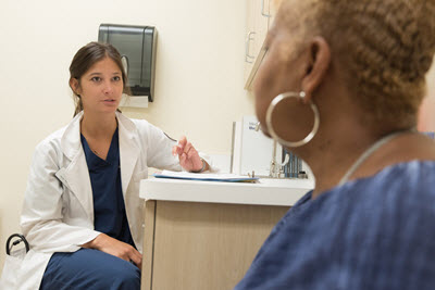 early career doctor is listening to her patient in the medical exam room